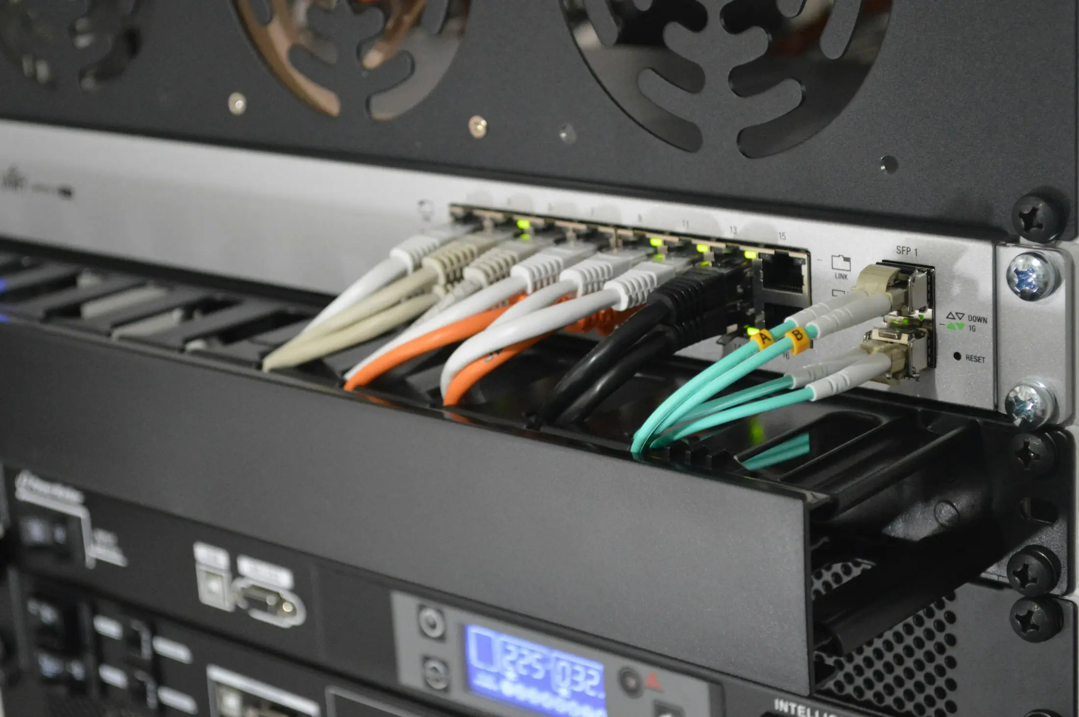 Câbles réseau et fibre optique raccordés sur un commutateur en baie